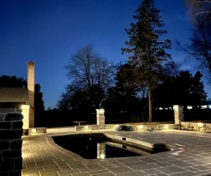 A finished masonry project around an inground pool at night