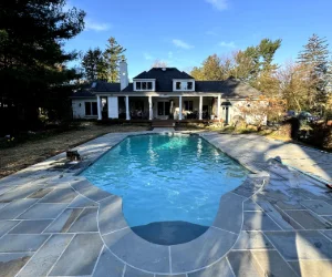 Light gray stone tiles with white grout surrounding a pool