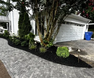 A walkway from a driveway to the front door made out of gray pavers