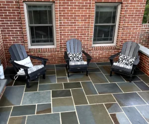 Dark multicolored stone tiles with white grout and a brick exterior wall of a residential home