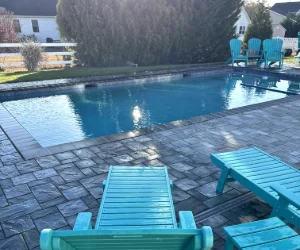 Dark gray stone bricks around an inground swimming pool done by Piazza Outdoor's masonry services